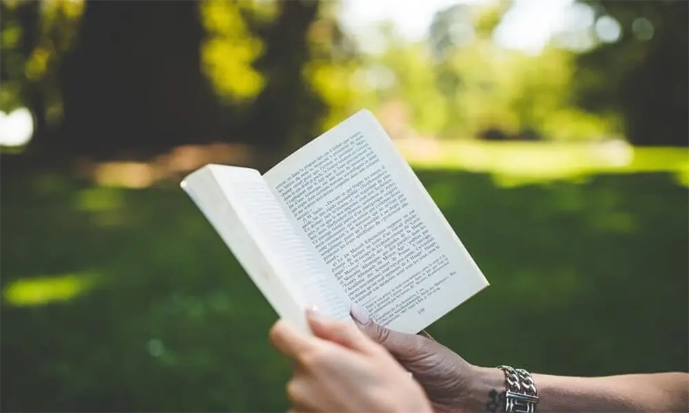 Reading open book in park.
